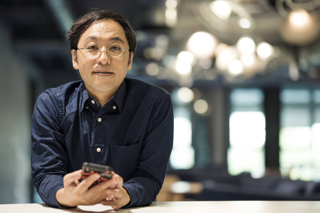 Portrait of an entrepreneur standing and holding a mobile phone in a modern office